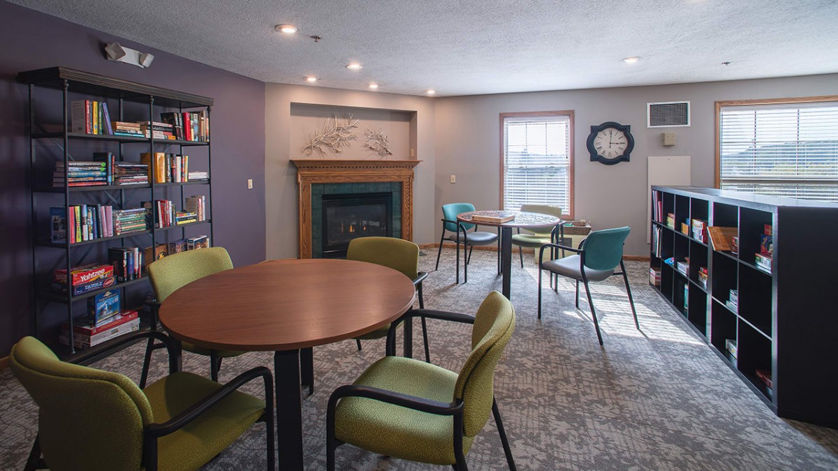 A cozy room with tables and chairs, featuring a fireplace and a window.
