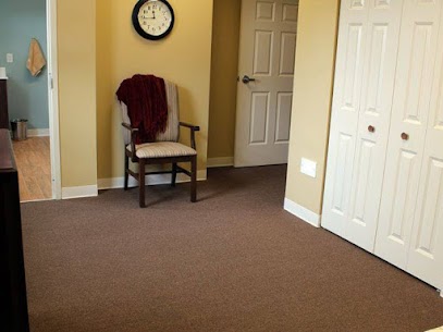 A cozy corner of a room featuring a chair, wall clock, and closed doors.