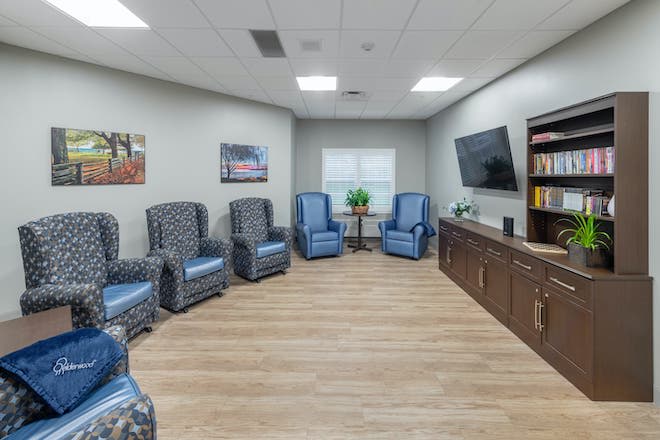 A modern waiting room with comfortable chairs, a television, and a bookshelf.