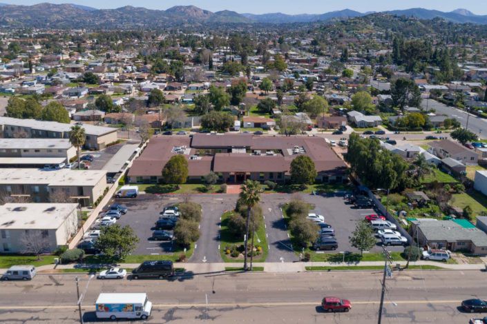 Aerial view of a suburban building with a parking lot and surrounding neighborhood.