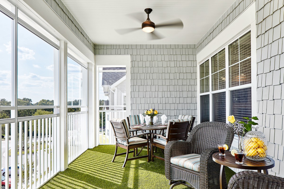 A cozy porch with comfortable seating, a dining table set, and ample natural light.