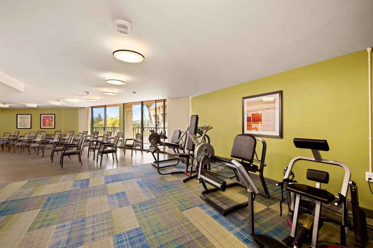 A well-lit fitness center equipped with various cardio machines and exercise equipment.