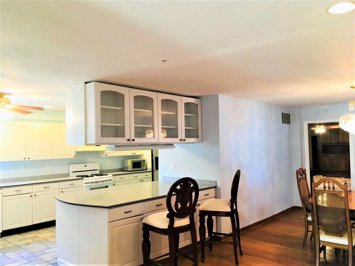 A modern kitchen with bar stools and an open layout connecting to the dining area.