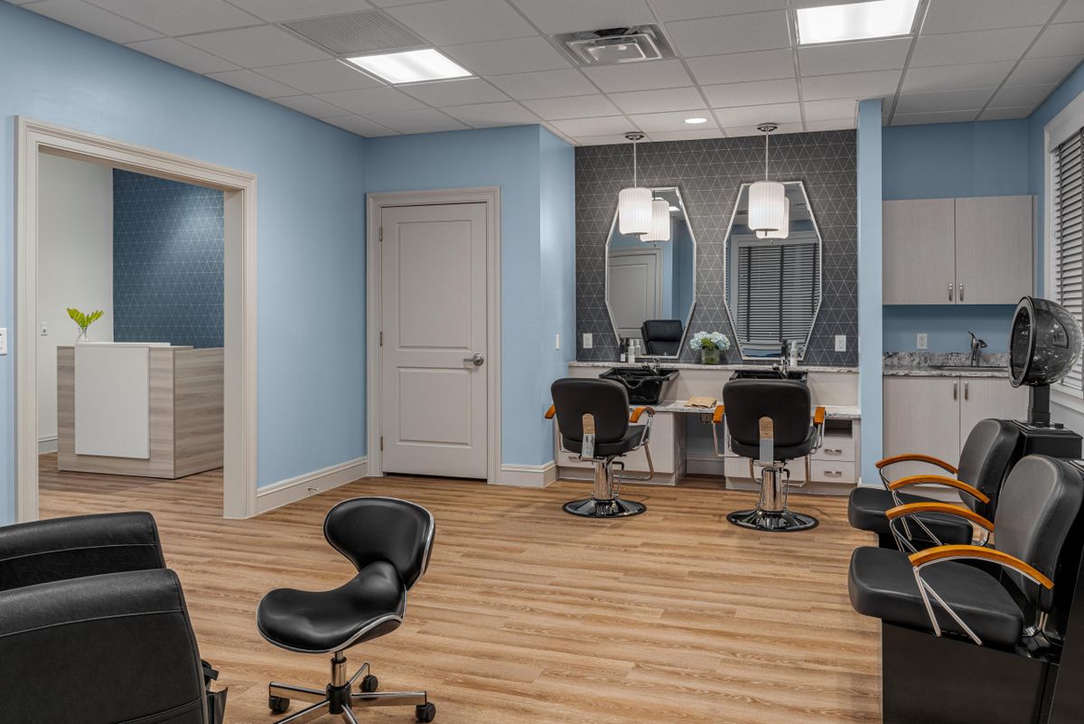 A modern salon interior with stylish chairs and mirrors, featuring wooden flooring and soft lighting.