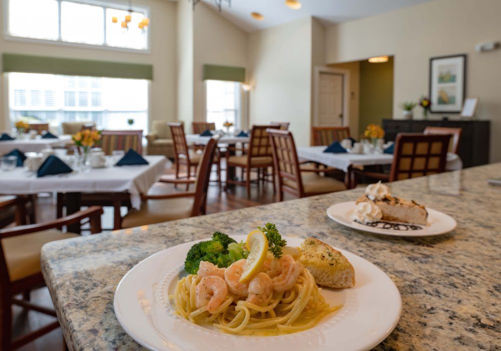 A plate of pasta with shrimp and broccoli in a restaurant dining area.