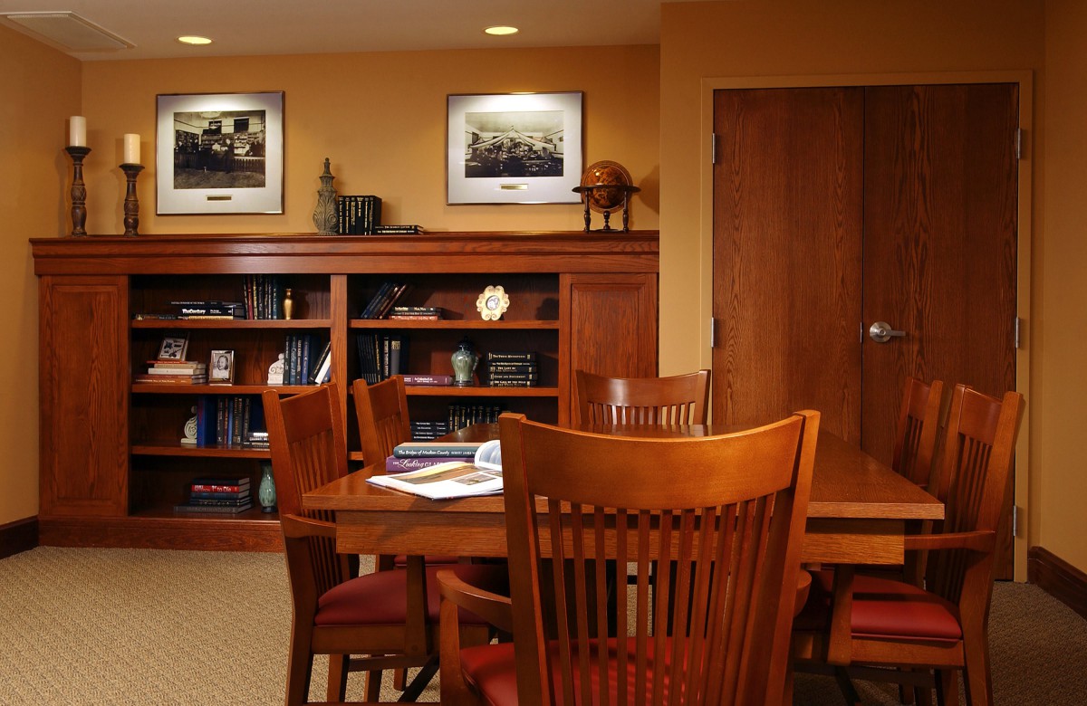 A wooden-furnished office conference room with a meeting table and bookshelves.