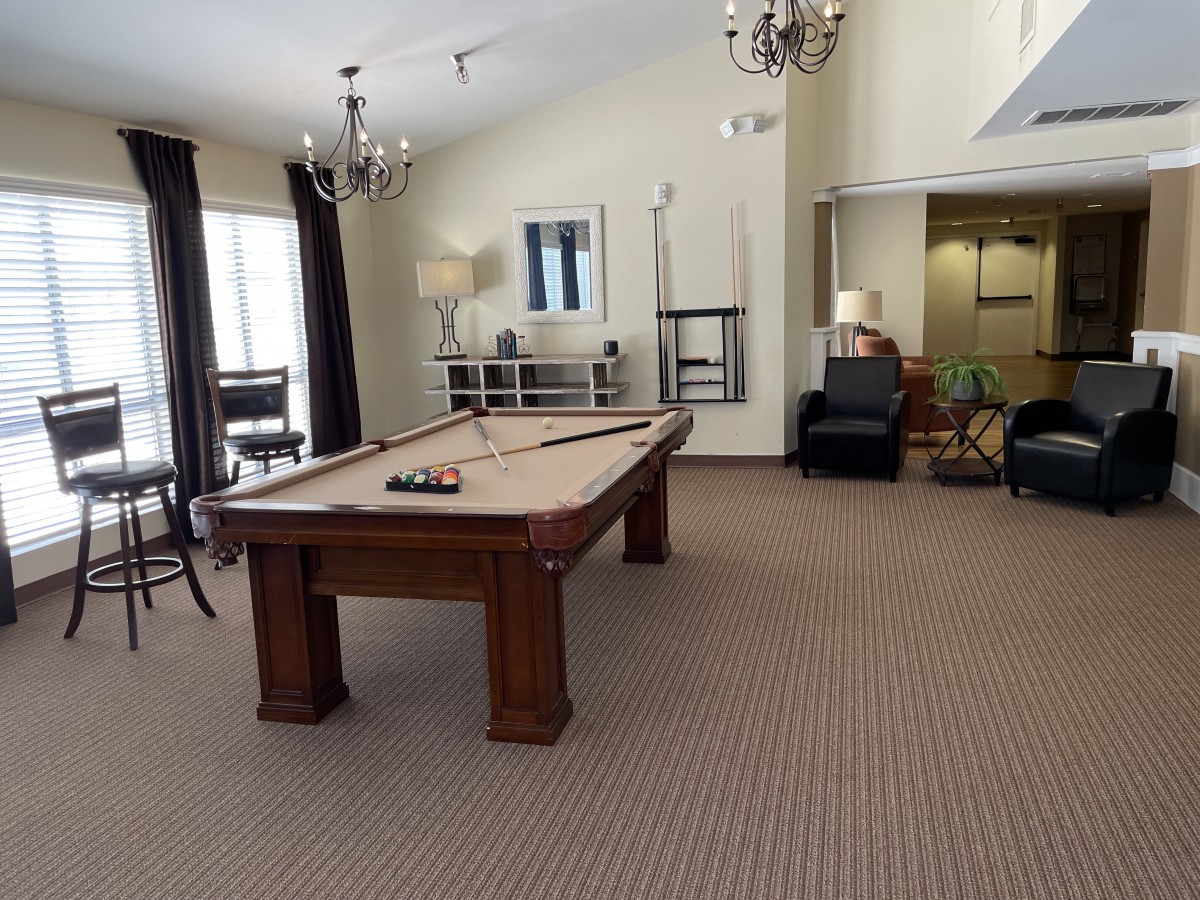 A spacious game room with a pool table and comfortable seating.