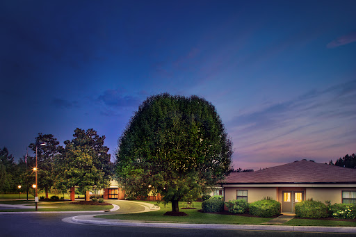A serene residential scene at twilight, featuring a well-maintained house surrounded by lush greenery.