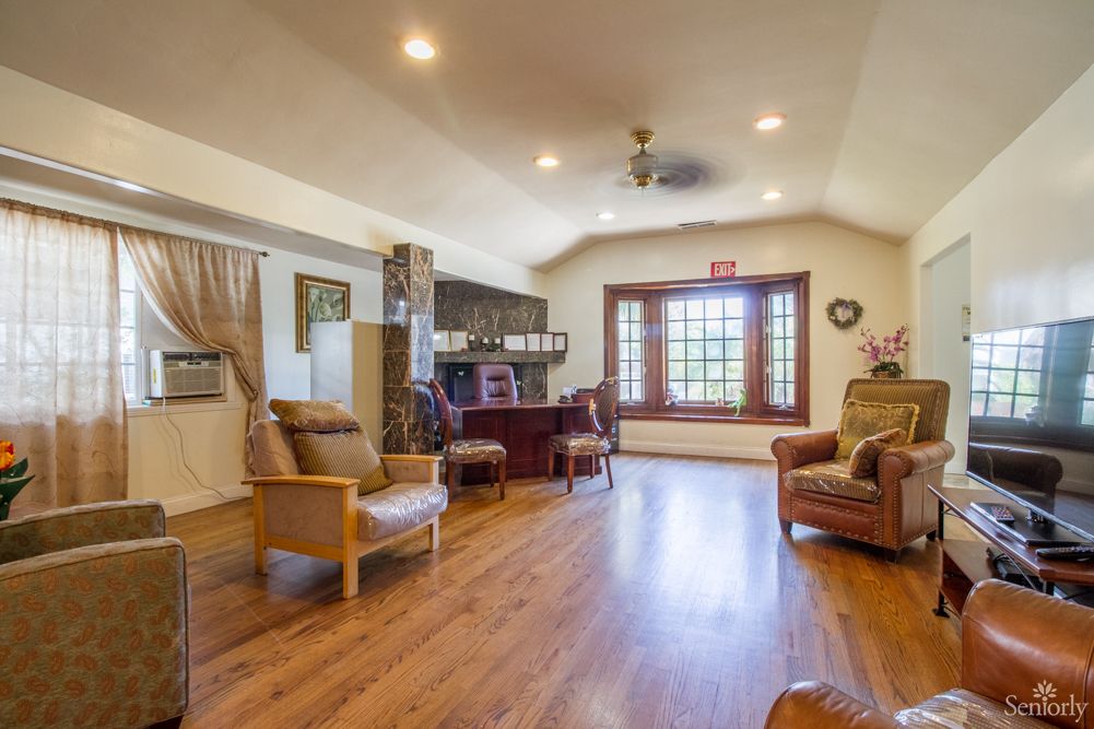A spacious living room with hardwood floors, comfortable seating, and large windows.