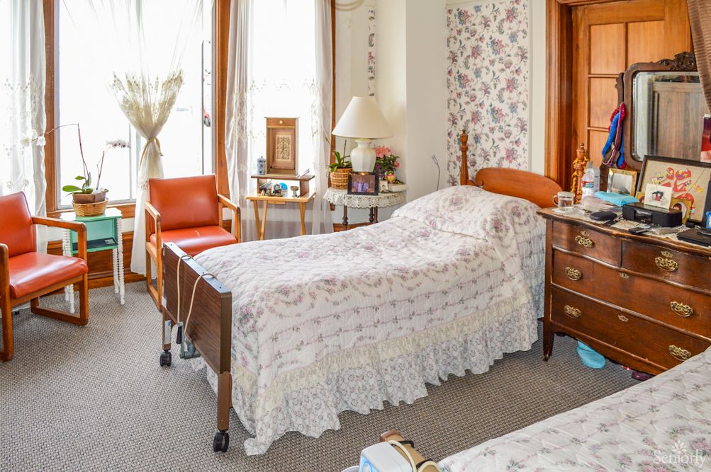 A cozy bedroom featuring a hospital bed with vintage decor and furniture.