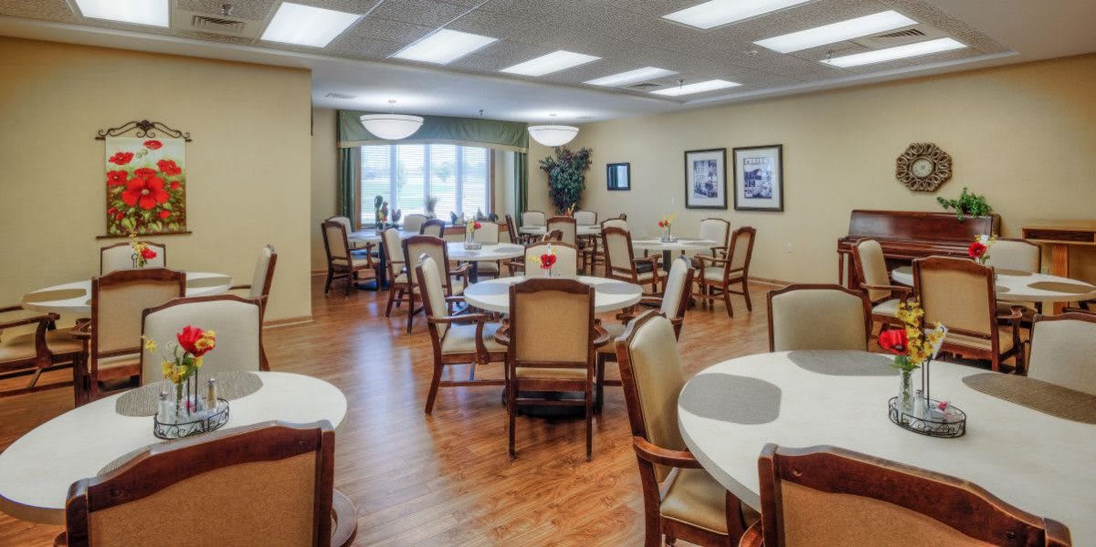 A neatly arranged dining room with multiple tables and chairs, featuring warm lighting and decor.
