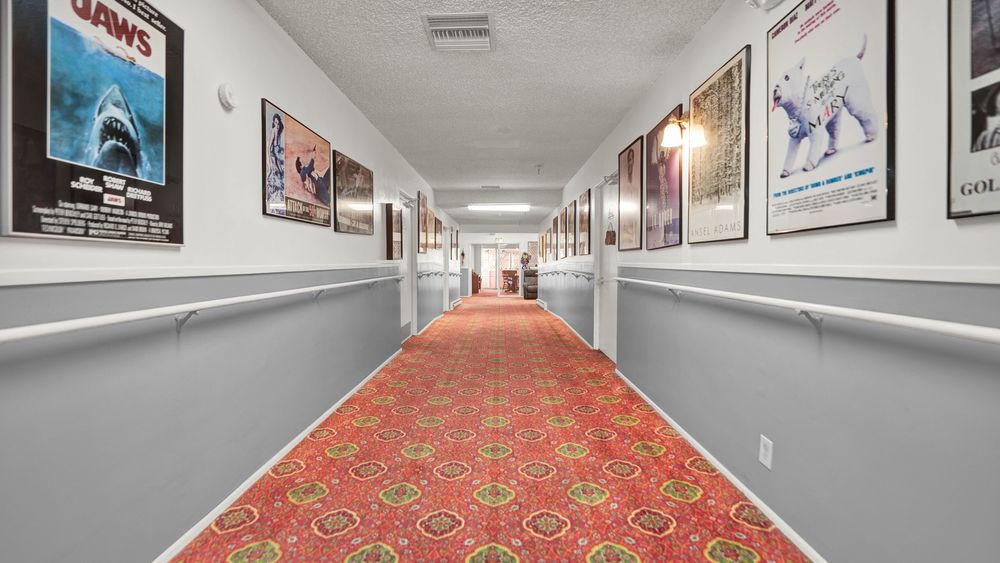 A long hallway adorned with colorful posters on the walls and a patterned carpet on the floor.