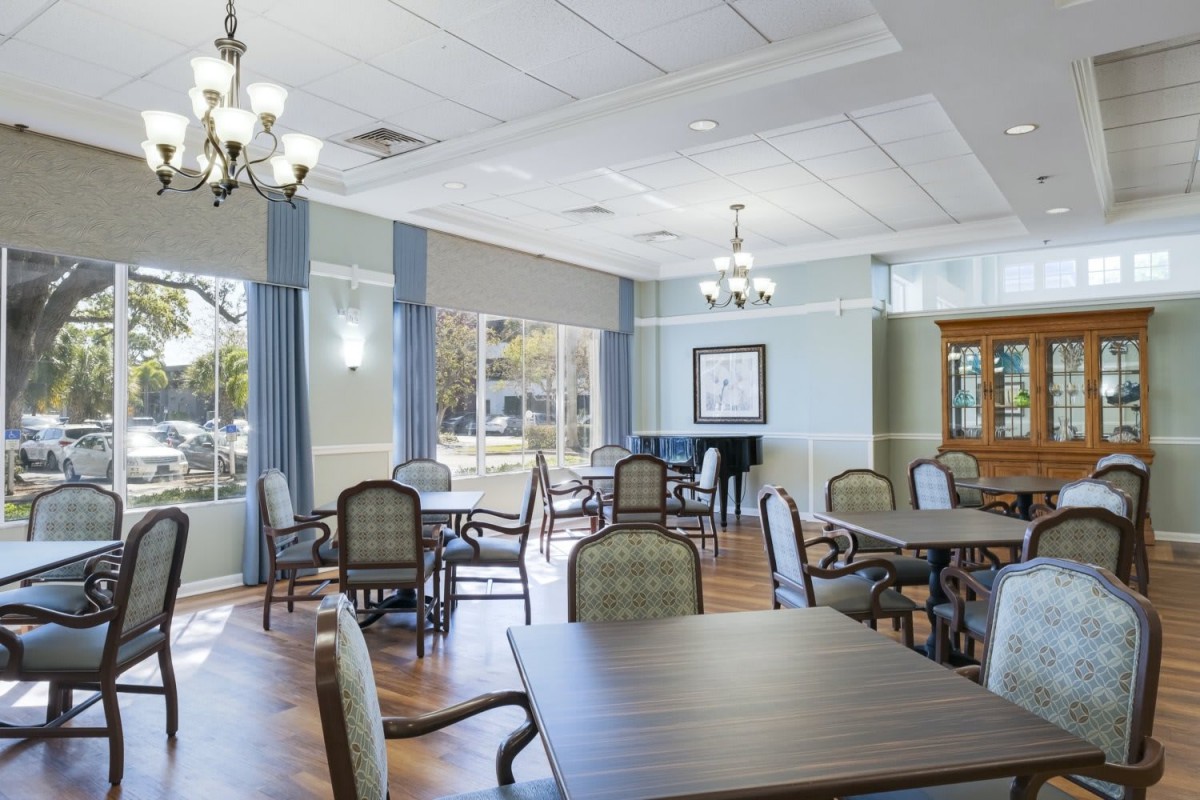 A spacious dining room with elegant chandeliers, comfortable chairs, and large windows providing natural light.