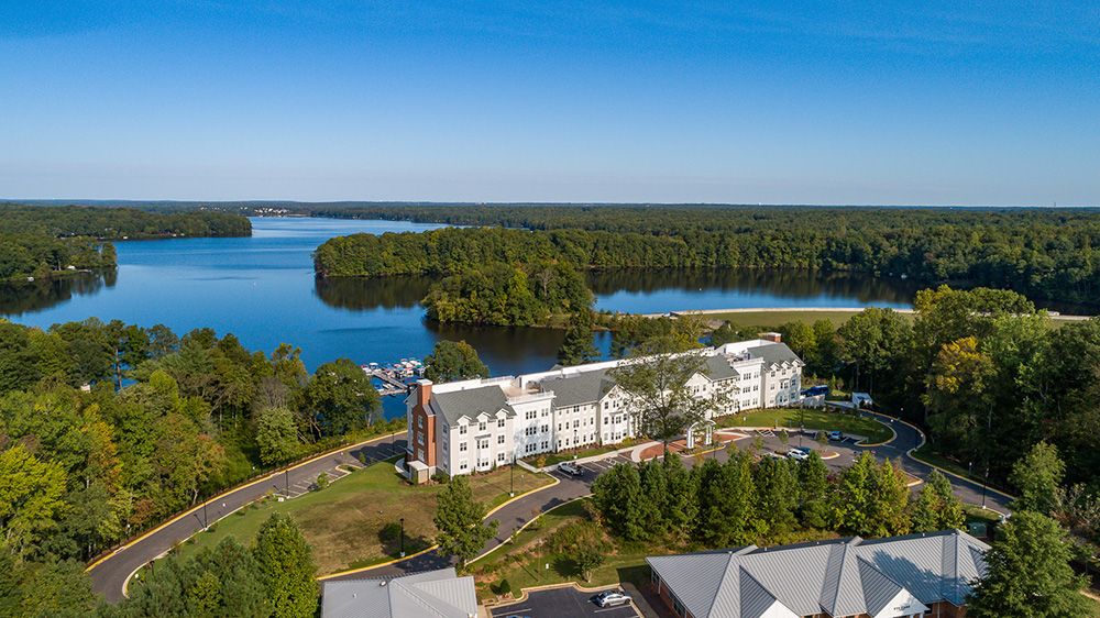 Aerial view of a lakeside hotel surrounded by lush forests and a large body of water.