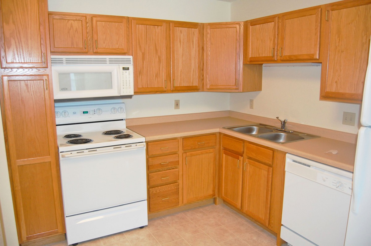 A kitchen featuring wooden cabinets, a white stove, microwave, sink, and dishwasher.