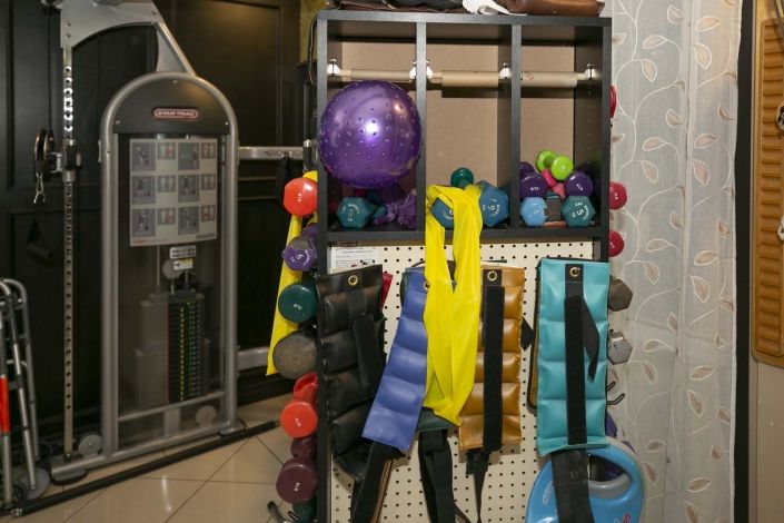 A variety of gym equipment including exercise balls, weights, and resistance bands organized on a rack.