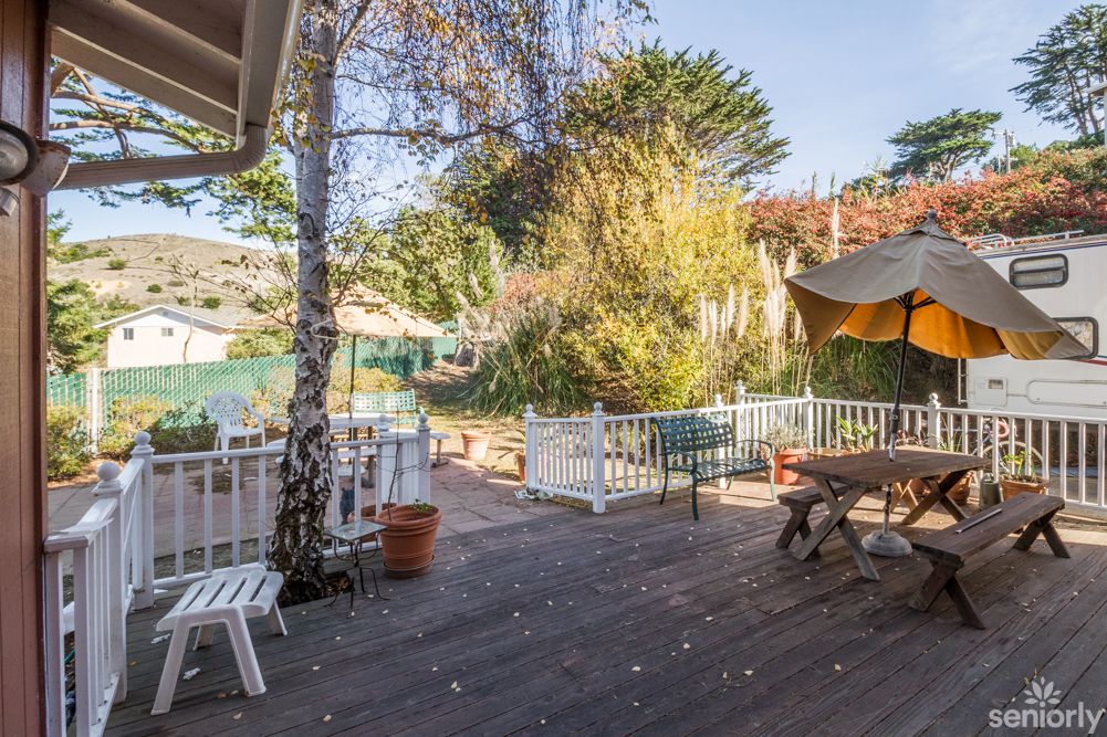 A sunny outdoor deck with patio furniture surrounded by trees, perfect for relaxation.