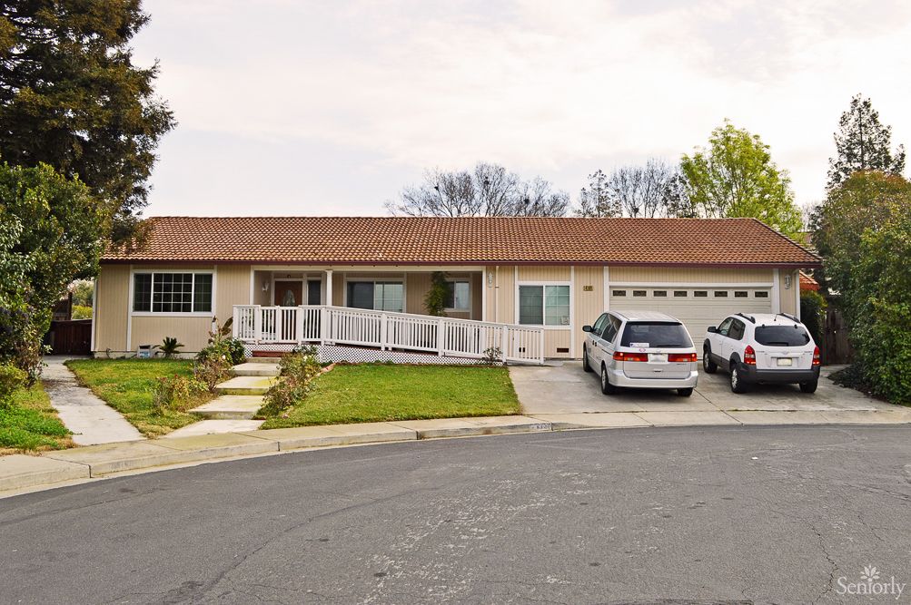A suburban single-story house with a driveway and two cars parked in front.