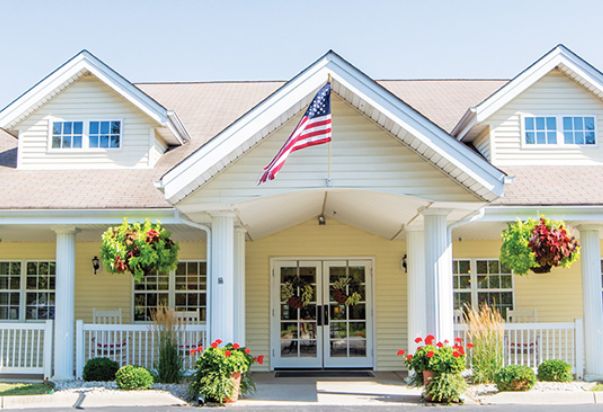A charming house entrance adorned with an American flag and vibrant flowers.