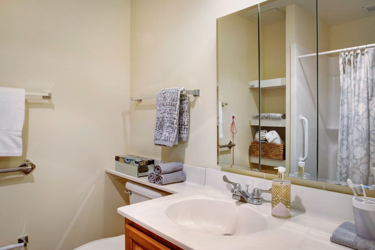A tidy bathroom with a sink, mirror, and neatly arranged towels.