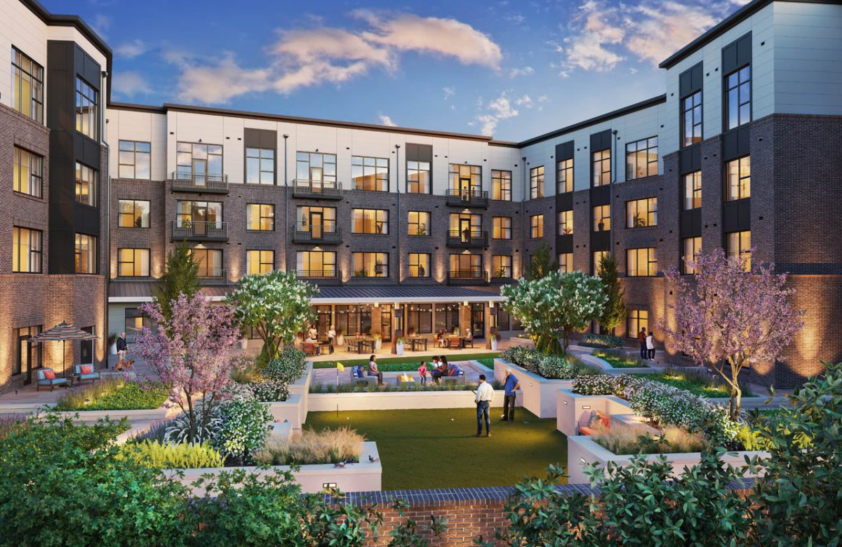 A modern apartment complex with a landscaped courtyard in the evening.