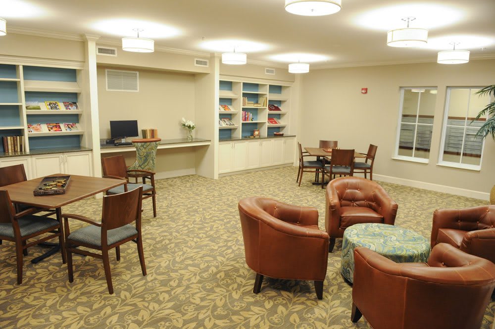 A cozy lounge area with bookshelves, tables, and chairs.