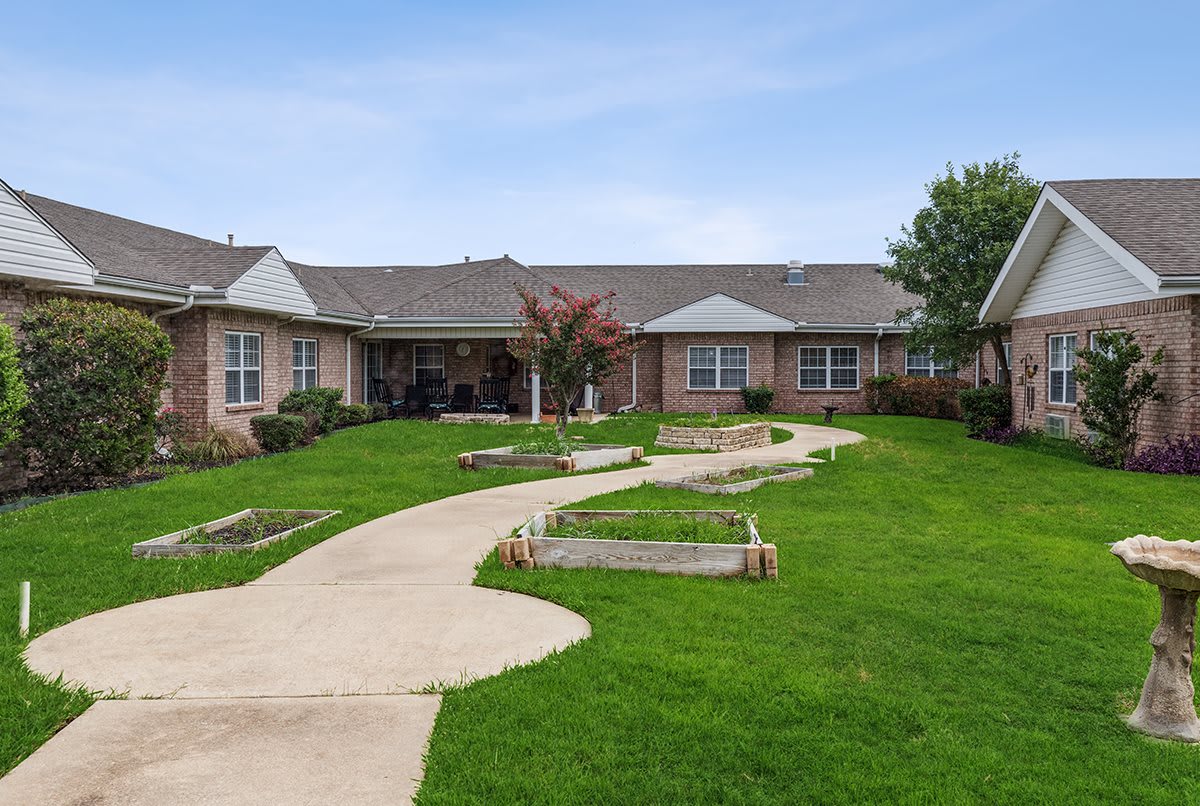 A single-story residential building with a well-maintained lawn and winding pathway.