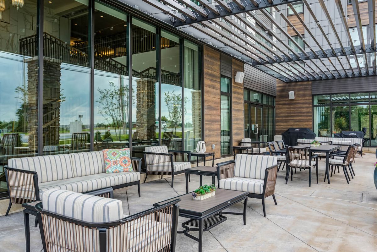 A modern patio with stylish outdoor seating, featuring cushioned chairs and tables under a pergola.
