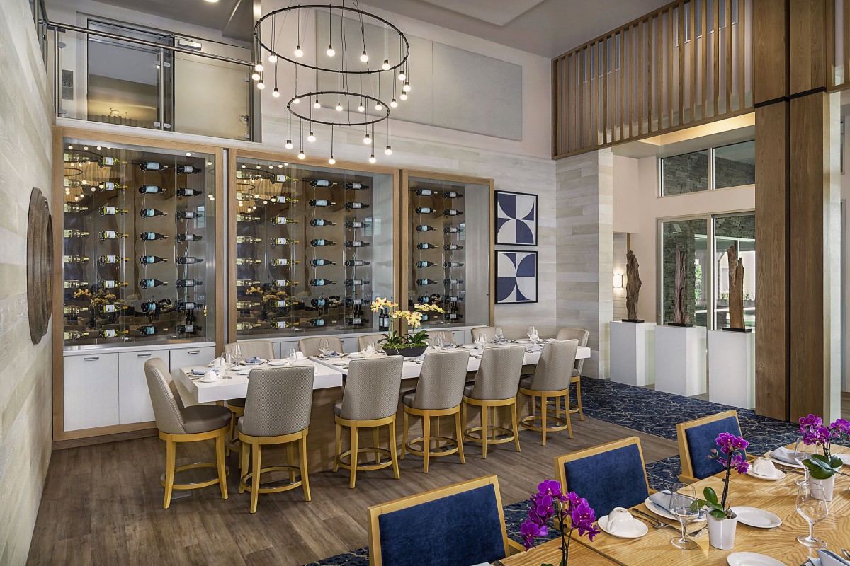 A luxurious dining room with elegant chandeliers and a modern wine storage display.