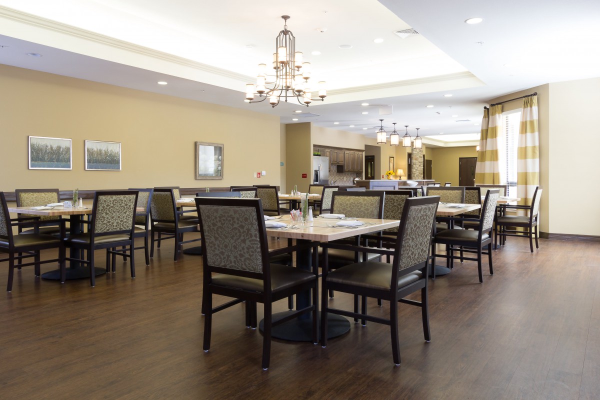 A spacious restaurant dining area with neatly arranged tables and chairs, featuring elegant chandeliers.
