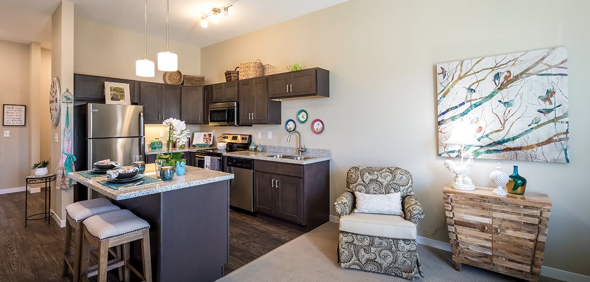 A modern open-space kitchen with dark cabinetry, a kitchen island, and a cozy armchair.