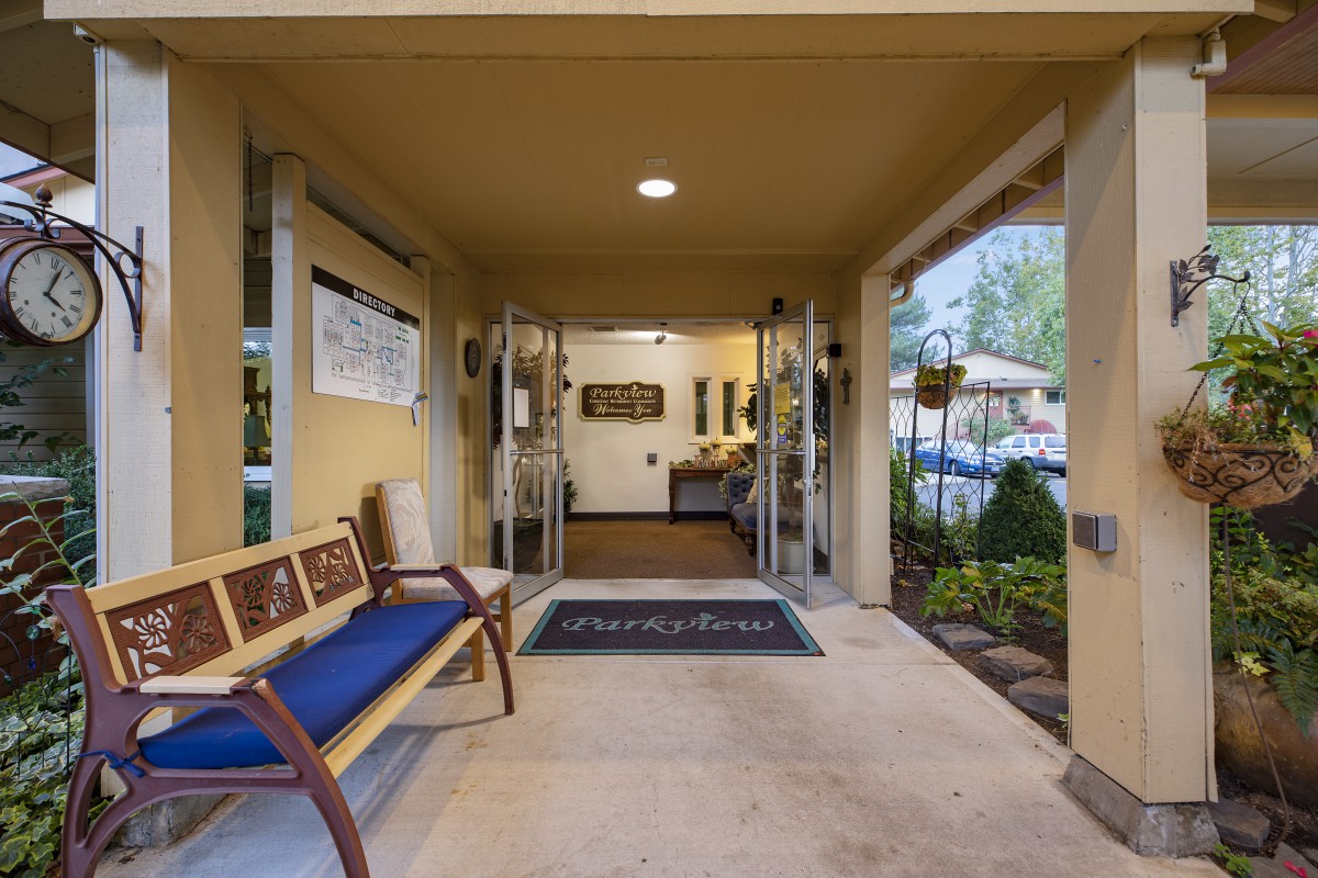 Welcoming entrance with a bench and greenery.