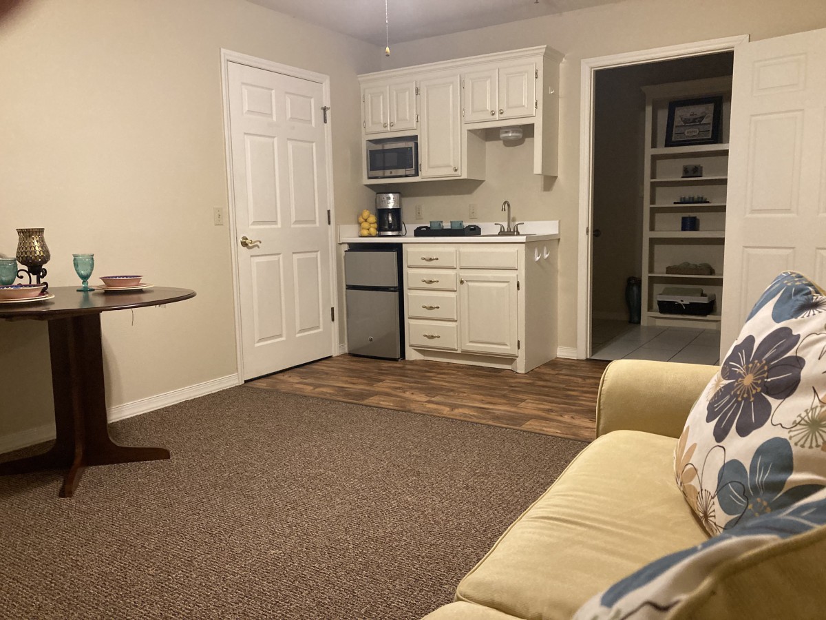 A cozy living space with a kitchenette, featuring a sofa and table.