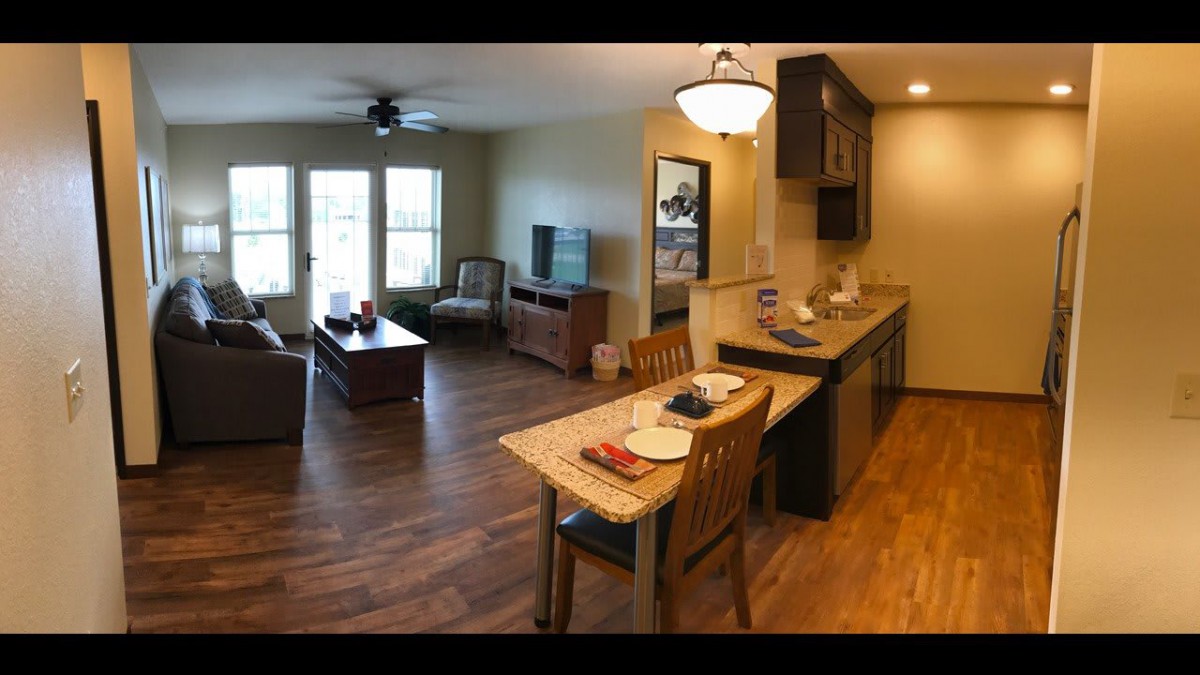 A cozy open floor plan living room and kitchen with wood flooring.