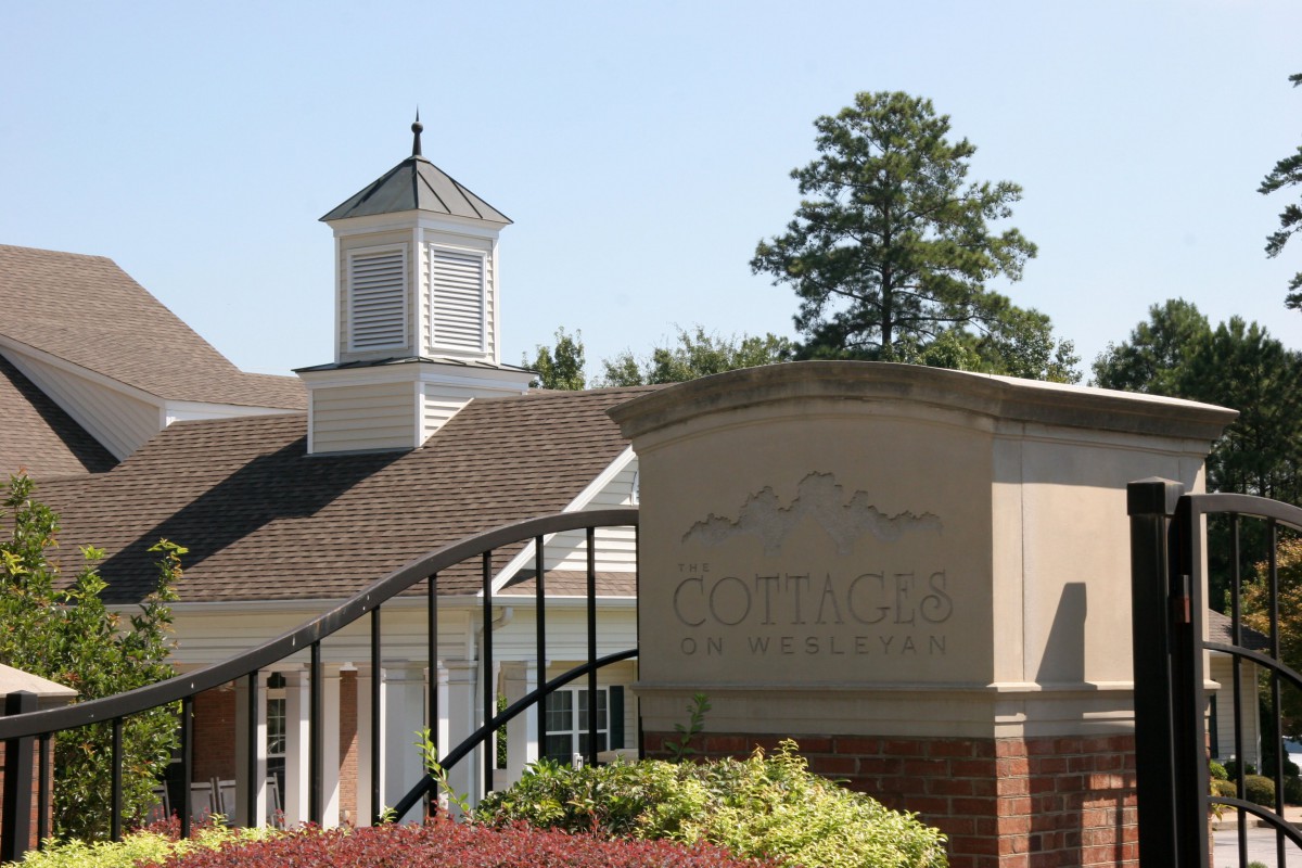 A building with a cupola in a landscaped setting, featuring a sign in the foreground.
