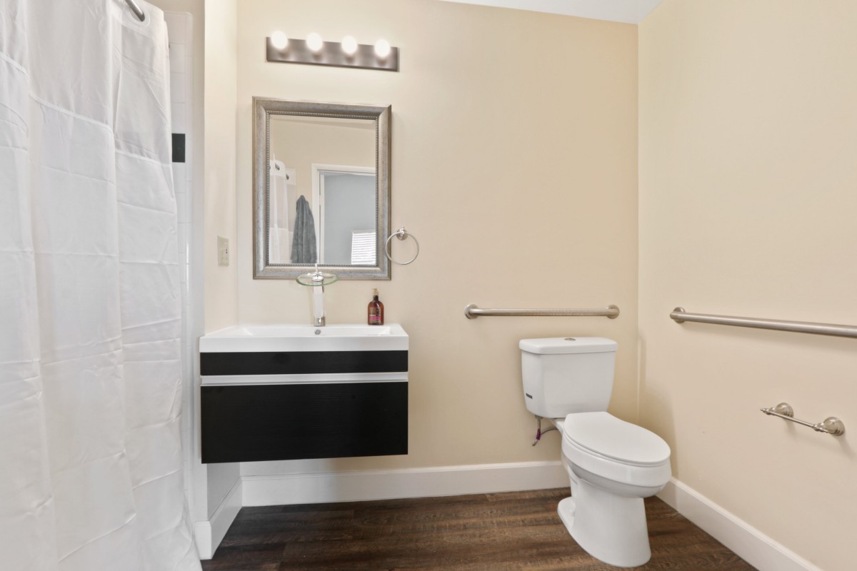 A modern bathroom with a wall-mounted sink, mirror, and toilet in a neutral color scheme.