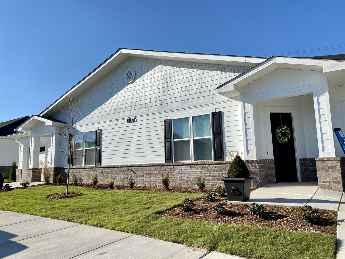 A single-story house with a well-kept lawn and front porch under a clear blue sky.