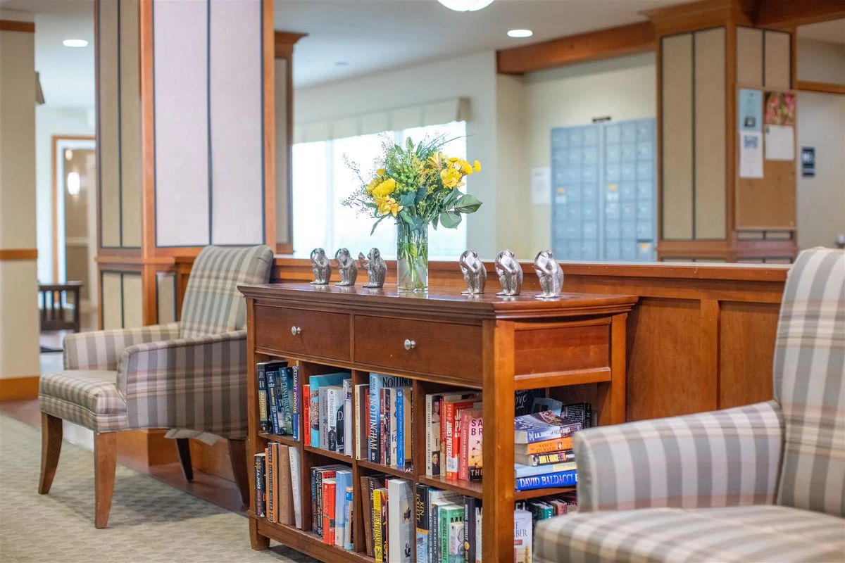A cozy indoor reading area with a wooden bookshelf and a vase of flowers.