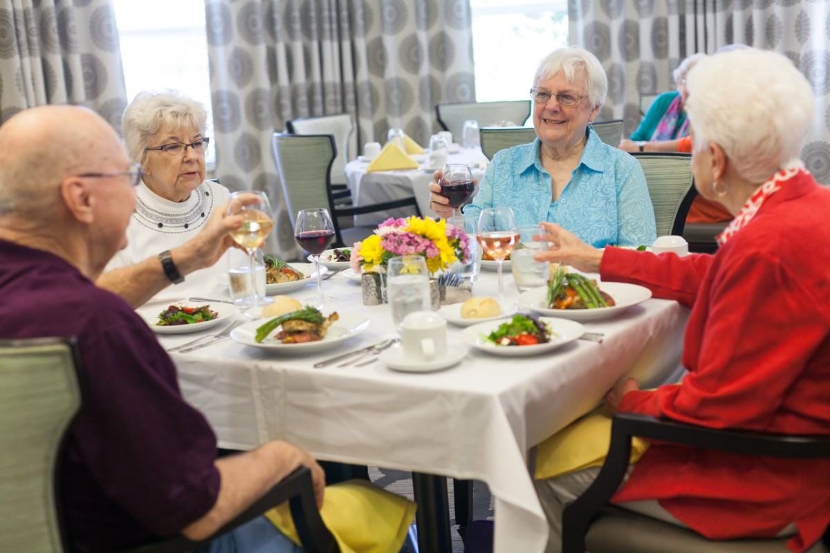 A group of seniors enjoying a meal and conversation at a dining table.
