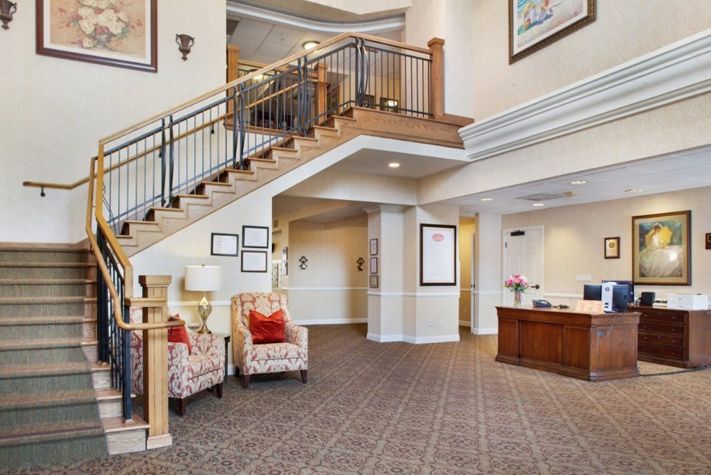 A spacious lobby featuring a staircase, reception desk, and modern furnishings.