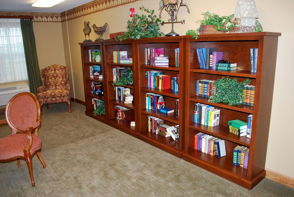 A cozy interior space featuring a wooden bookshelf filled with books and decorative items.