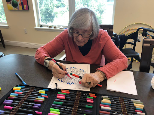 A senior woman engages in a creative coloring activity, surrounded by an array of colorful markers.