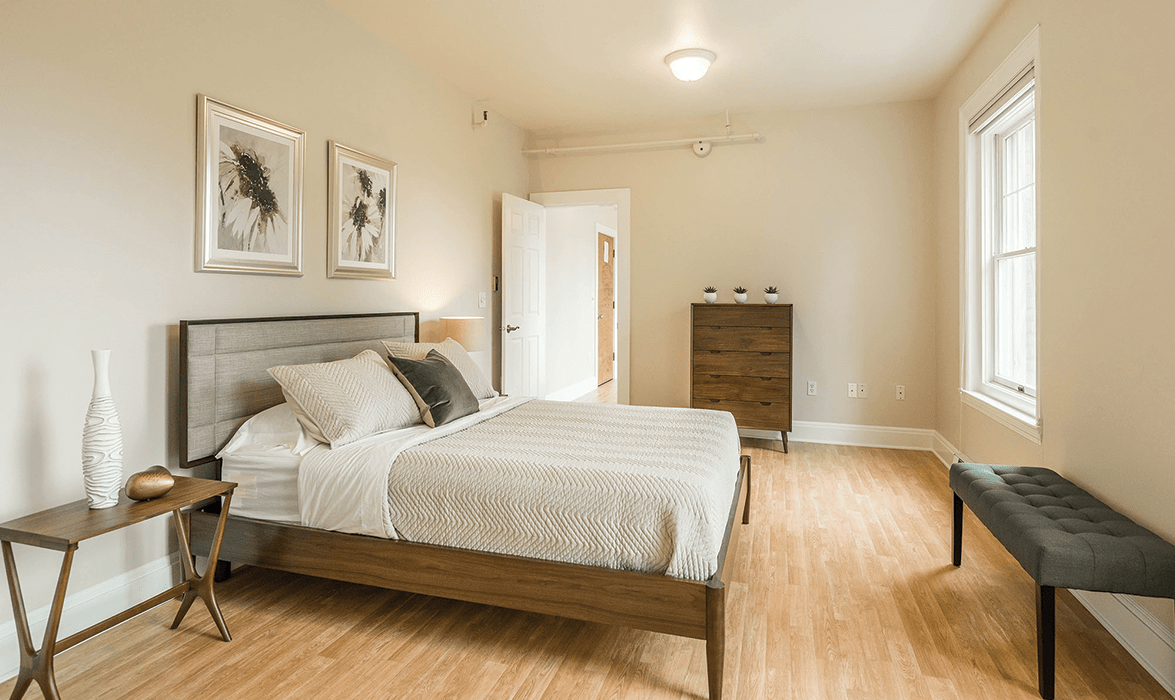 A modern and minimalist bedroom with neutral tones and wooden flooring.