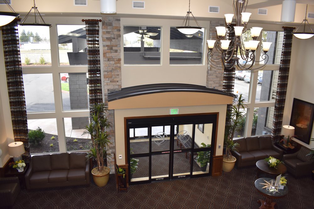 A modern lobby area with large windows, decorative lighting, and plants near the entrance.