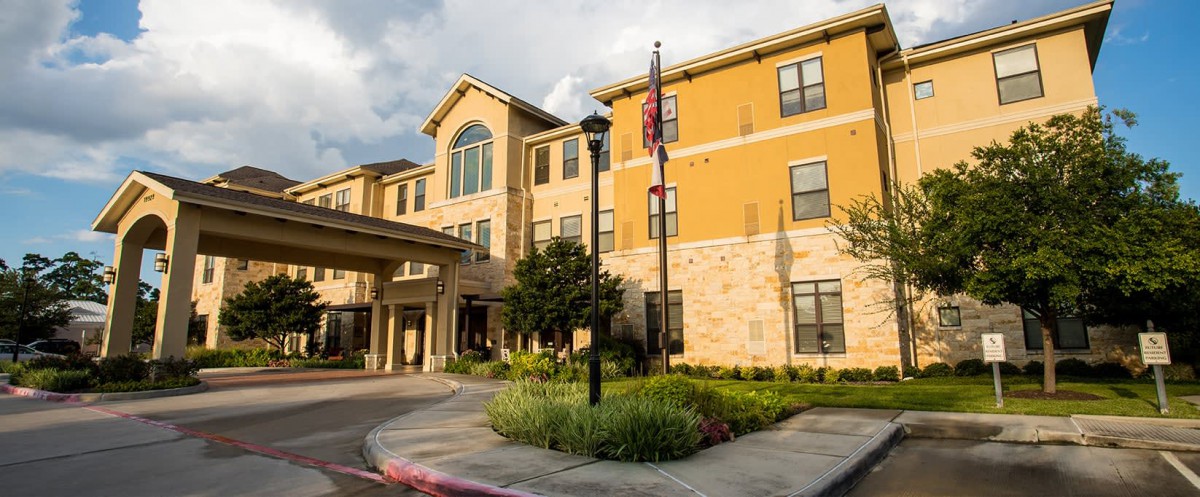 A modern residential building with a welcoming entrance and neatly landscaped surroundings.