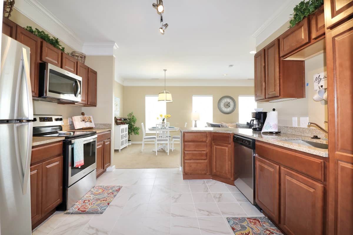 A modern kitchen with wooden cabinets and stainless steel appliances, leading into a bright dining area.