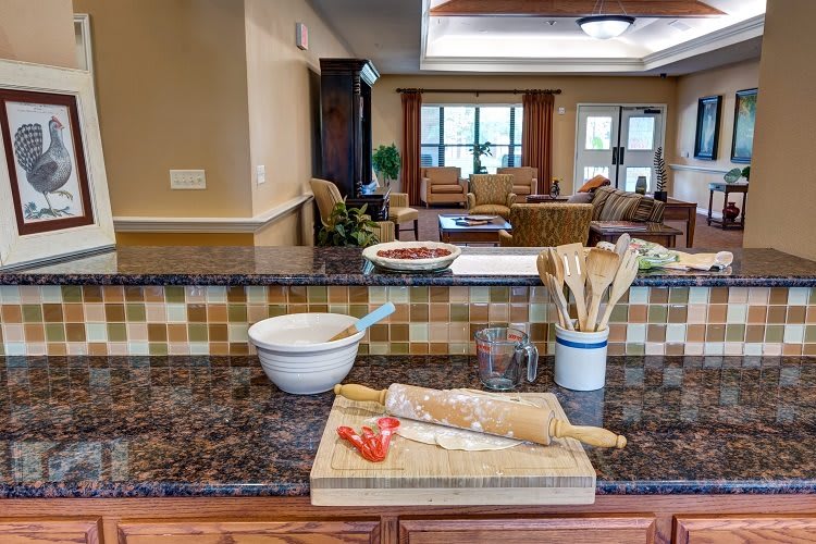 A kitchen countertop with a cutting board, bread, and utensils in preparation.