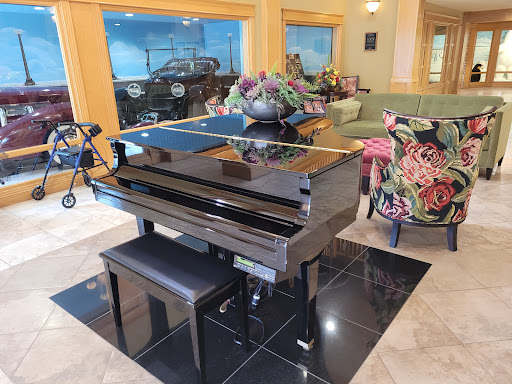 A polished black piano in a stylish living space, surrounded by elegant furniture and floral decor.