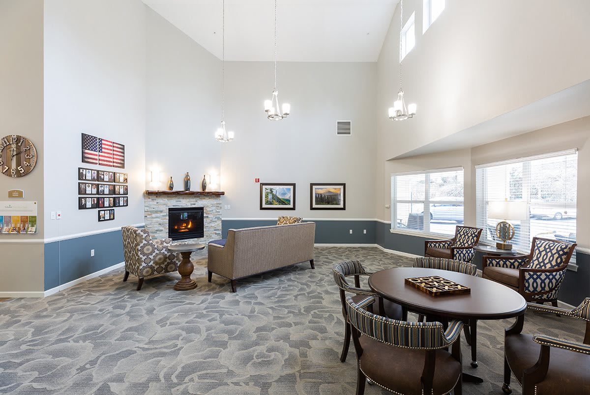 A spacious living room with a high ceiling, featuring a cozy fireplace, comfortable seating, and large windows.