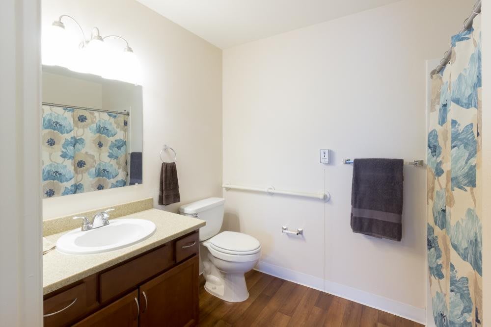 A clean and simple bathroom interior with a sink, toilet, and wooden flooring.